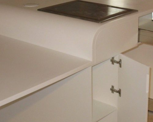 Bílá kuchyňská linka s vestavěnými zásuvkami a deskou