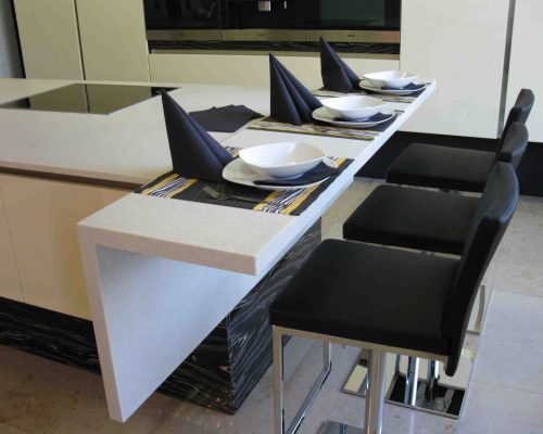 Barový pult s bílou deskou a černými židlemi