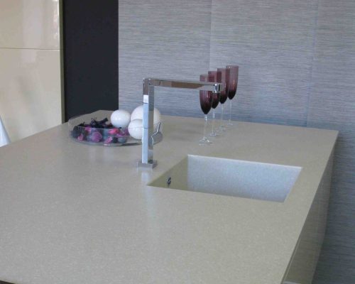 Moderní šedý dřez zapuštěný do pracovní desky s baterií