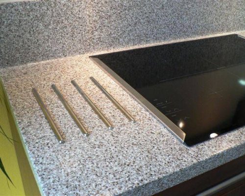 Detail kuchyňské pracovní desky s výřezy a tmavým dekorem