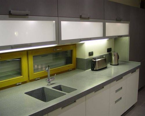 Moderní kuchyňská linka s bílými skříňkami a žlutým obkladem