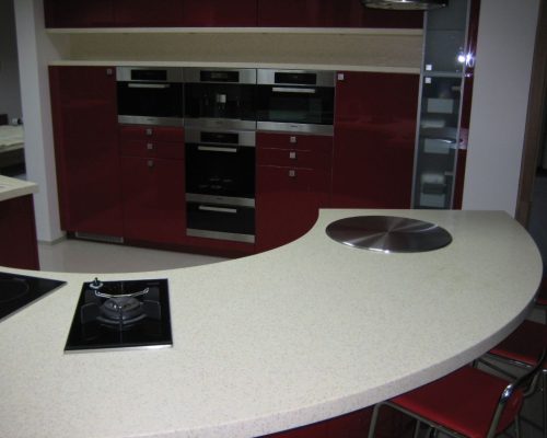 Červená kuchyňská linka s černou deskou a vestavěnou troubou