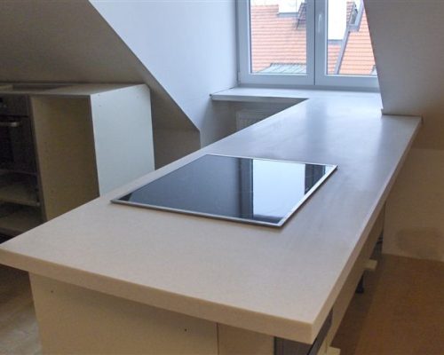 Moderní kuchyňská linka s bílou deskou a varnou deskou u okna