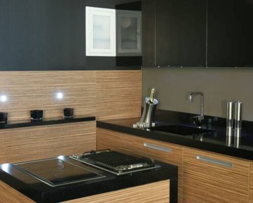 Tmavá kuchyň s hnědým obkladem a plynovým sporákem