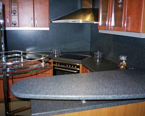 Rohová kuchyňská deska s tmavým obkladem a varnou deskou